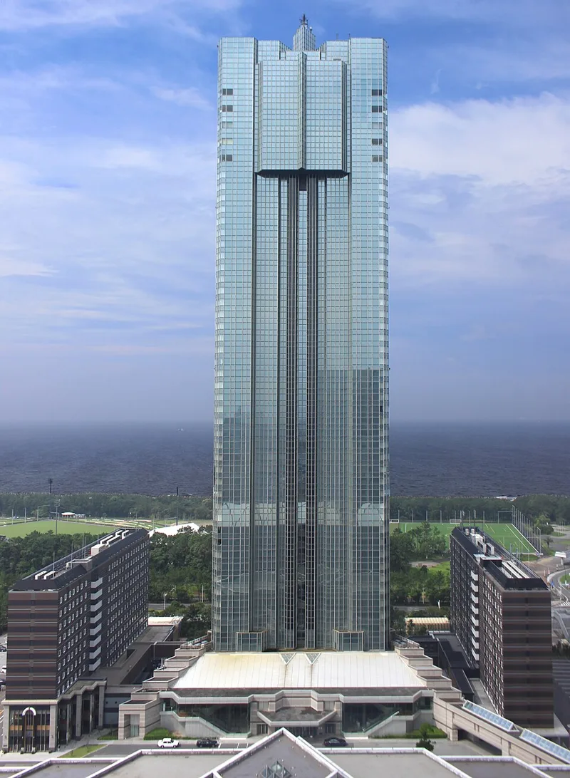 海を背にそびえるアパホテル＆リゾート〈東京ベイ幕張〉のセントラルタワー。ガラス張りの高層ビルの両側に低層棟が並ぶ